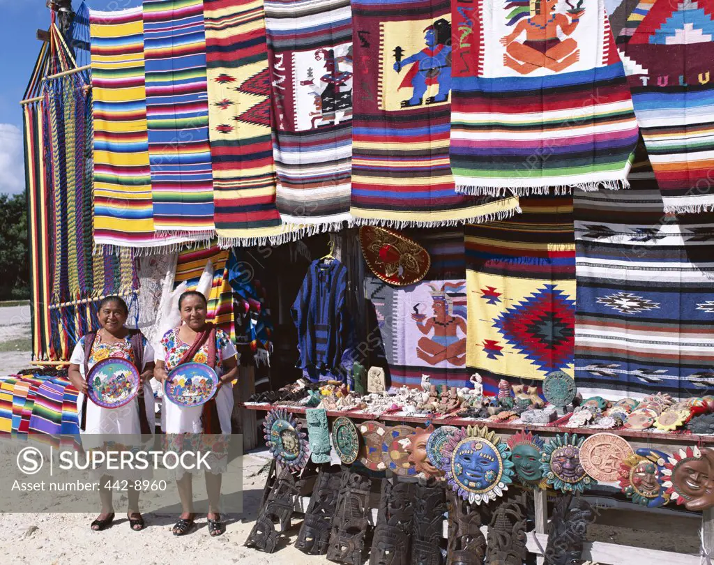 Two female vendors dressed in Mayan costumes displaying products, Cancun, Mexico