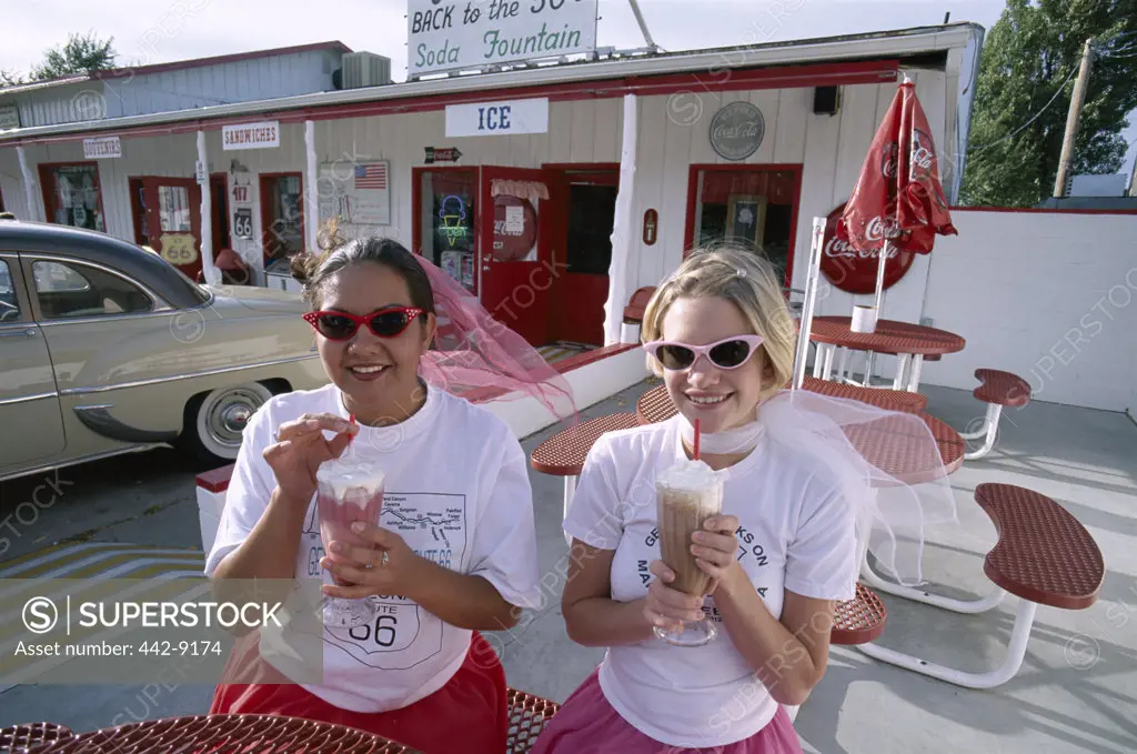 Two teenage girls sitting holding ice cream floats, Twisters Soda Fountain, Route 66, Williams, Arizona, USA