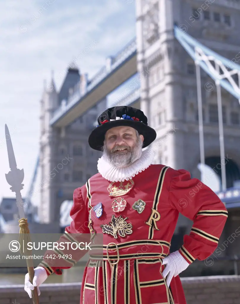 Portrait of a Beefeater standing in front of the Tower Bridge, London, England
