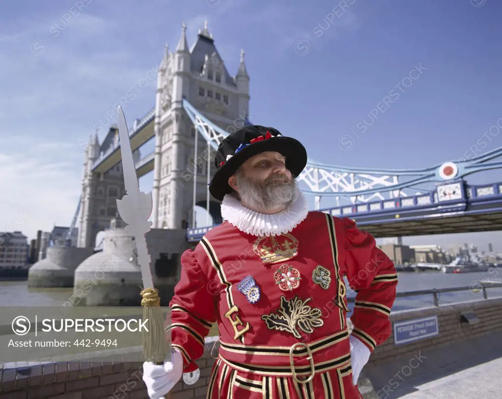 Beefeater standing in front of the Tower Bridge, London, England