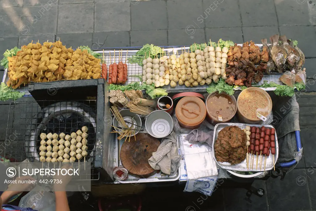 High angle view of a person's hand cooking kebabs on a street stall, Bangkok, Thailand