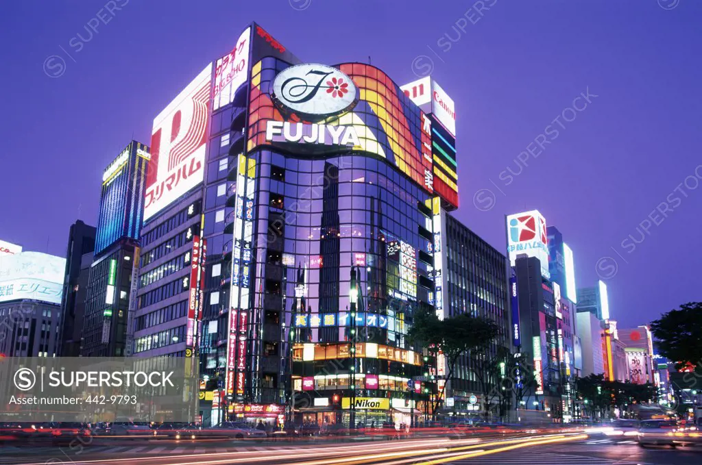 Low angle view of buildings lit up at dusk, Tokyo, Japan
