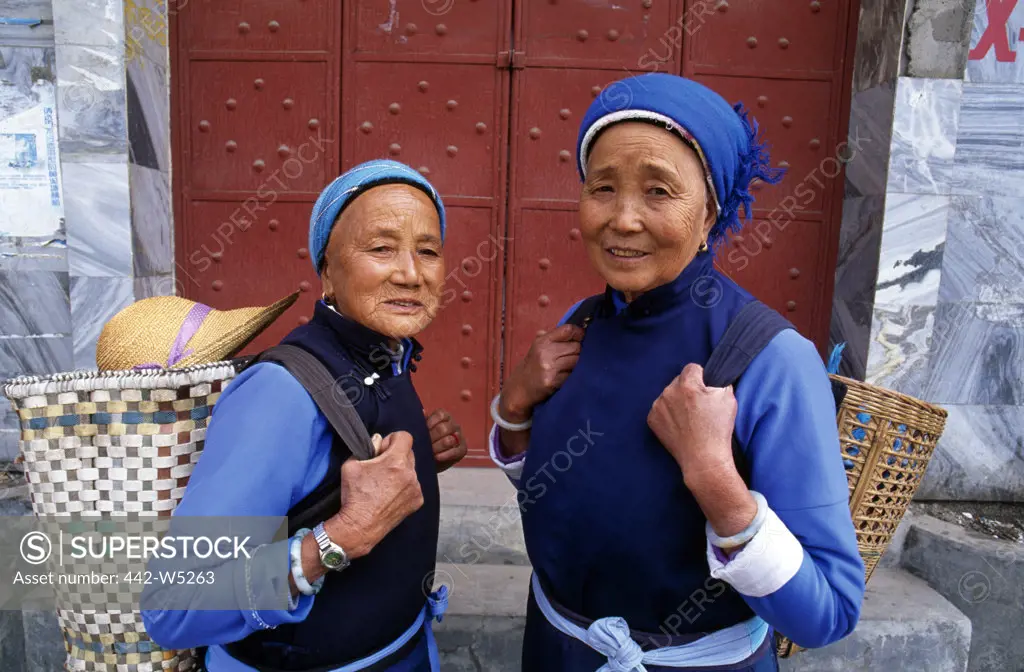 Portrait of two senior women carrying cane baskets, Dali, China