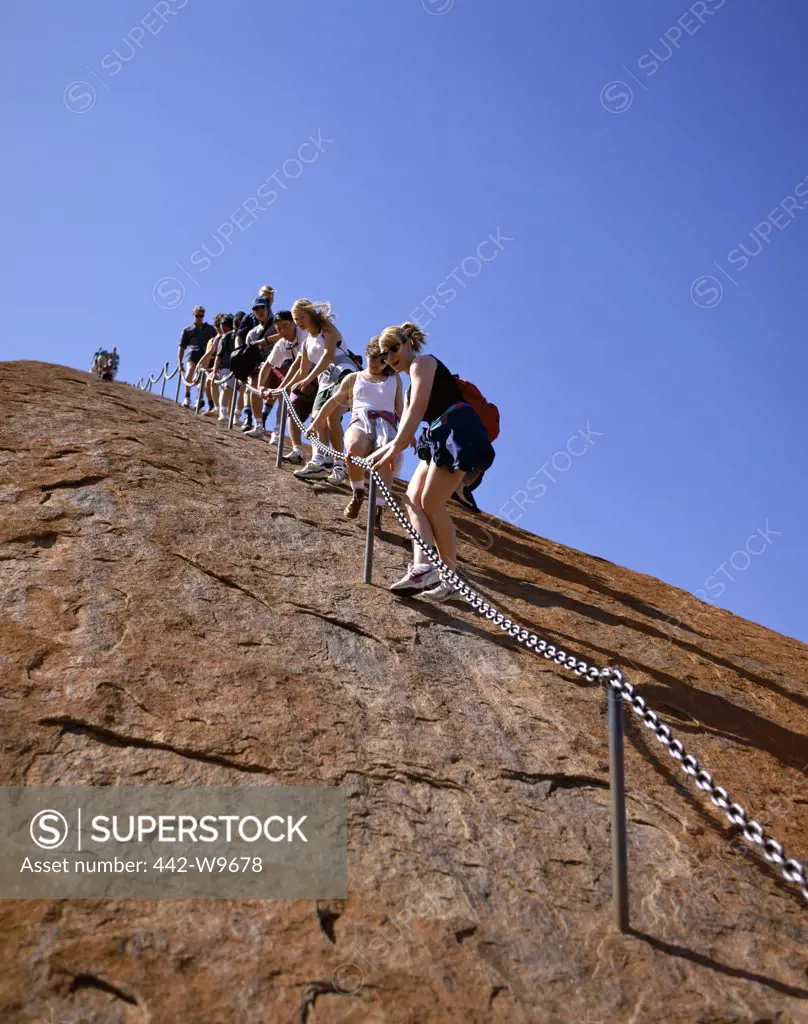 Tourists climbing a rock, Ayers Rock, Uluru-Kata Tjuta National Park, Northern Territory, Australia