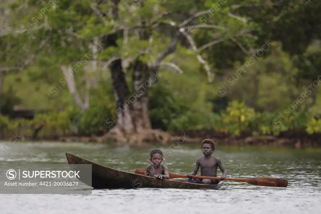 Two boys paddling dugout canoe, Kolombangara Island, Solomon Islands, April 