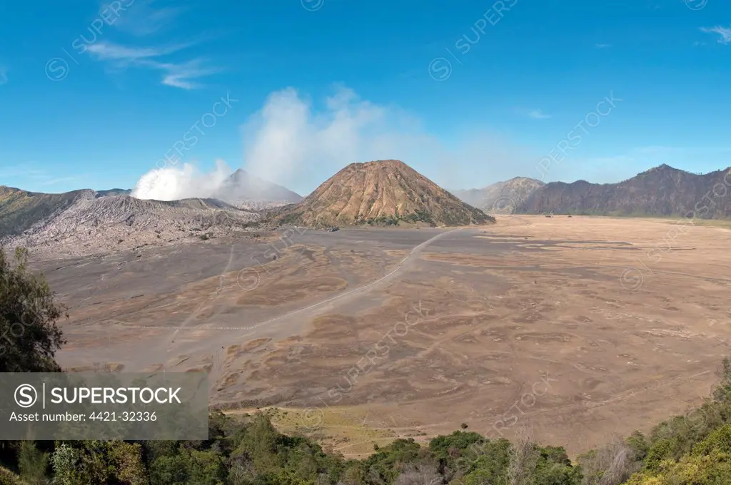 View across plain towards volcanoes, 'Sea of Sand', Mount Bromo (left) and Mount Batok (right), Mount Semeru in distance, Bromo Tengger Semeru N.P., East Java, Indonesia