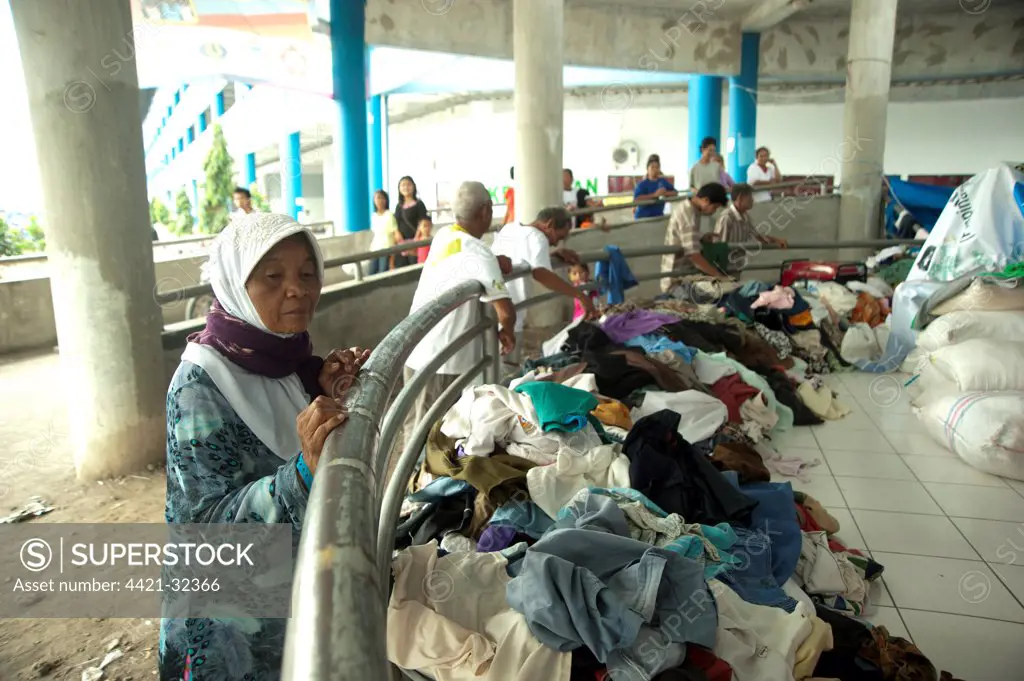 Old woman looking at clothes for refugees from recent volcanic eruption, Maguwo, Mount Merapi, Central Java, Indonesia, november 2010