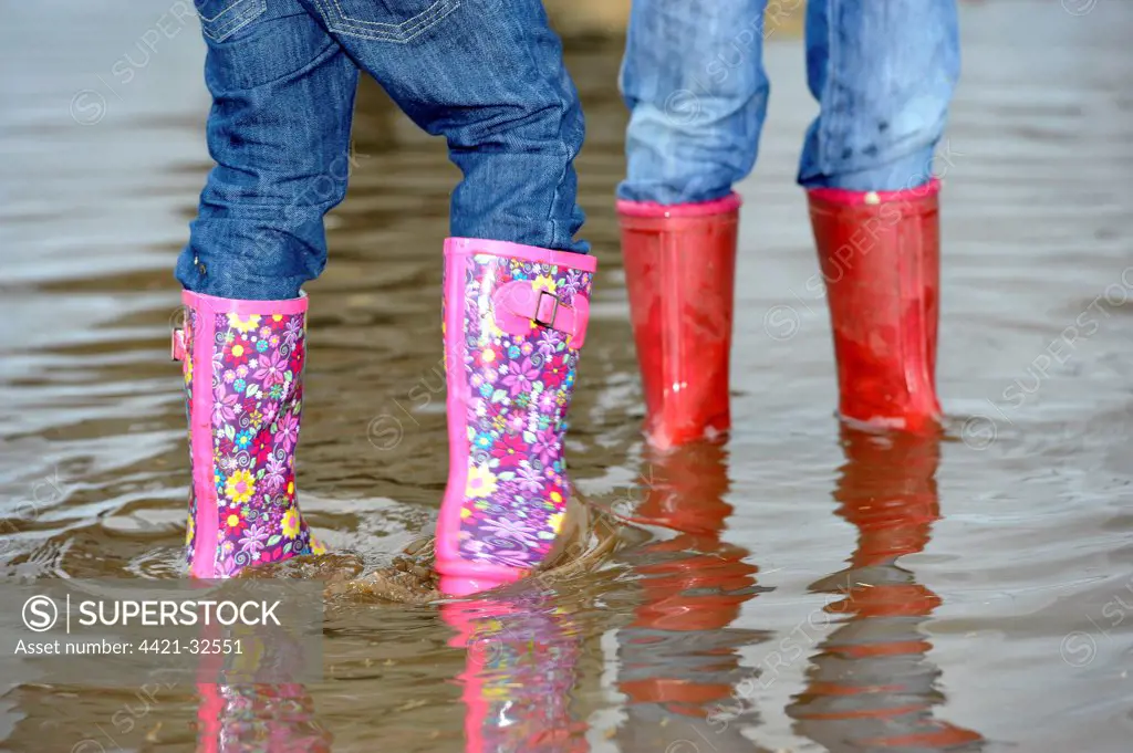 Children playing in puddle, wearing colourful wellington boots, Great Britain, june