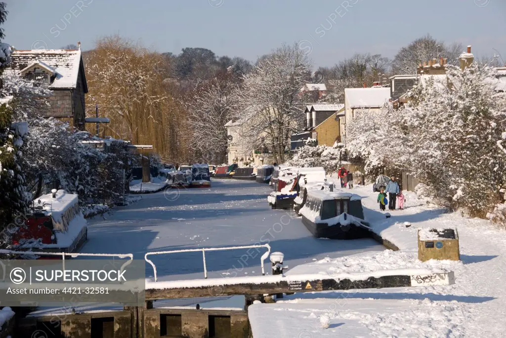 Canalside path, narrowboats and locks in snow, Grand Union Canal, Berkhamsted, Hertfordshire, England, winter