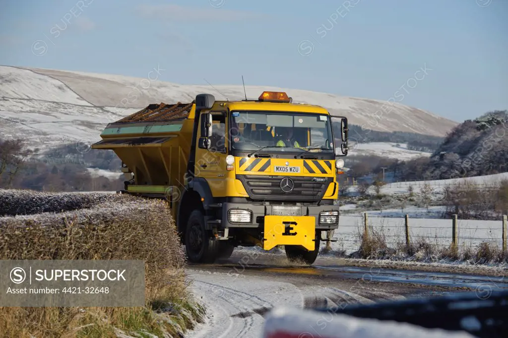 Council gritter lorry gritting snow covered rural road, Whitewell, Lancashire, England, november