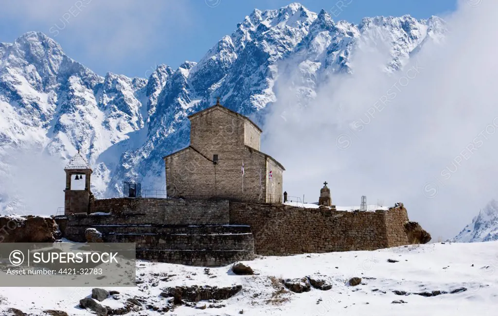 Monastery in village with snow covered mountains, near Kazbegi, Great Caucasus, Caucasus Mountains, Georgia, april