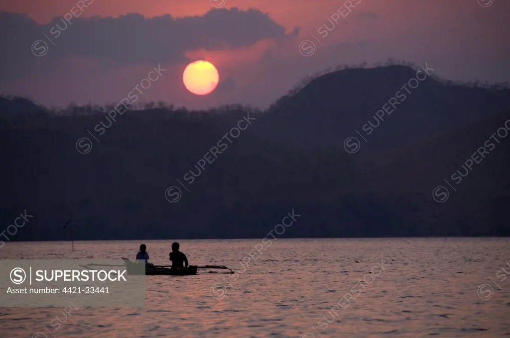 Silhouette of fishermen and canoe at sunset, near Lewaling Village, Lembata Island, Solor Archipelago, Lesser Sunda Islands, Indonesia