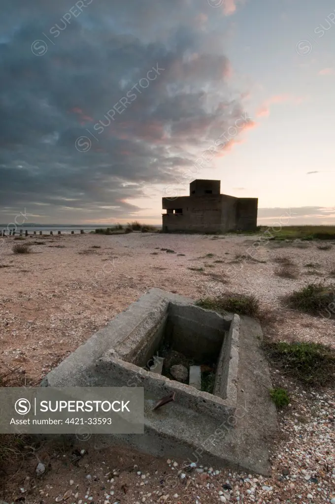 Remains of WWII block-house on shingle beach at sunset, The Swale National Nature Reserve, Isle of Sheppey, Kent, England, autumn