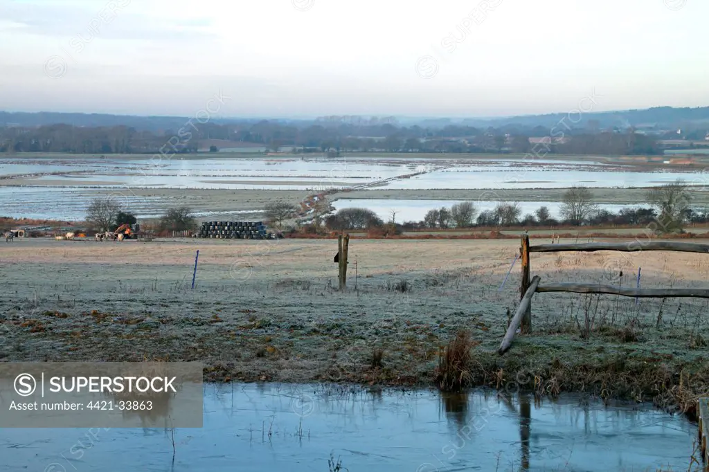 View of frost covered pasture towards flooded watermeadow habitat, Pulborough Brooks RSPB Reserve, West Sussex, England, december