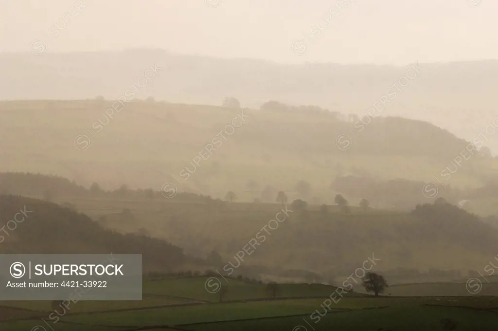 View of misty farmland at sunset, looking towards Bakewell, Peak District, Derbyshire, England, march