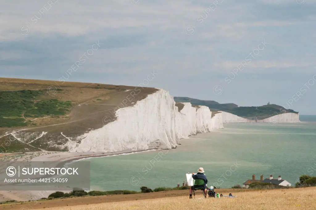 Artist with easel, painting chalk sea cliffs, Seven Sisters, Seaford, South Downs N.P., East Sussex, England, july
