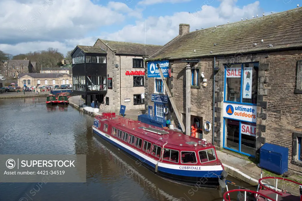 Tour boat and narrowboats moored on canal in town, Leeds and Liverpool Canal, Skipton, North Yorkshire, England, march