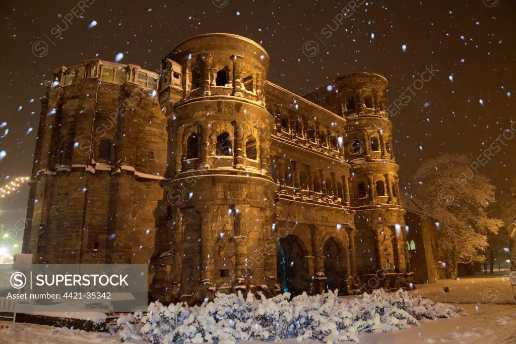 Roman city gate illuminated during snowfall at night, Porta Nigra, Trier, Rhineland-Palatinate, Germany, december