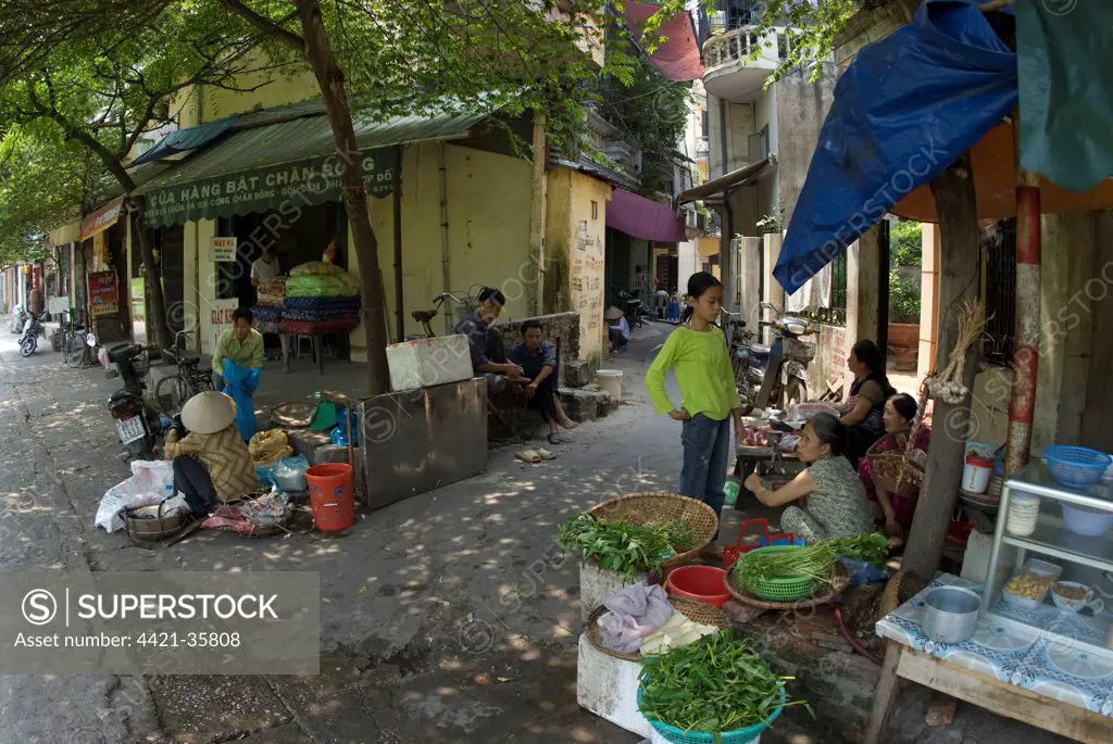 Woman selling vegetables on city street, Hanoi, Vietnam