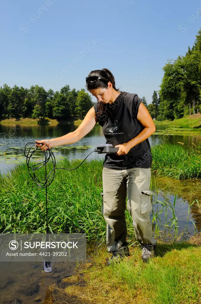 Biologist checking water quality in montane lake, Italy
