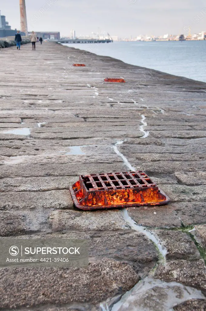 Grate covering glass plate measuring rate of cracking in granite sea wall protecting harbour entrance, sea wall preventing sand encroachment from South Bull sandbank at Sandymount, Great South Wall, Dublin Port, Dublin Bay, Ireland, november
