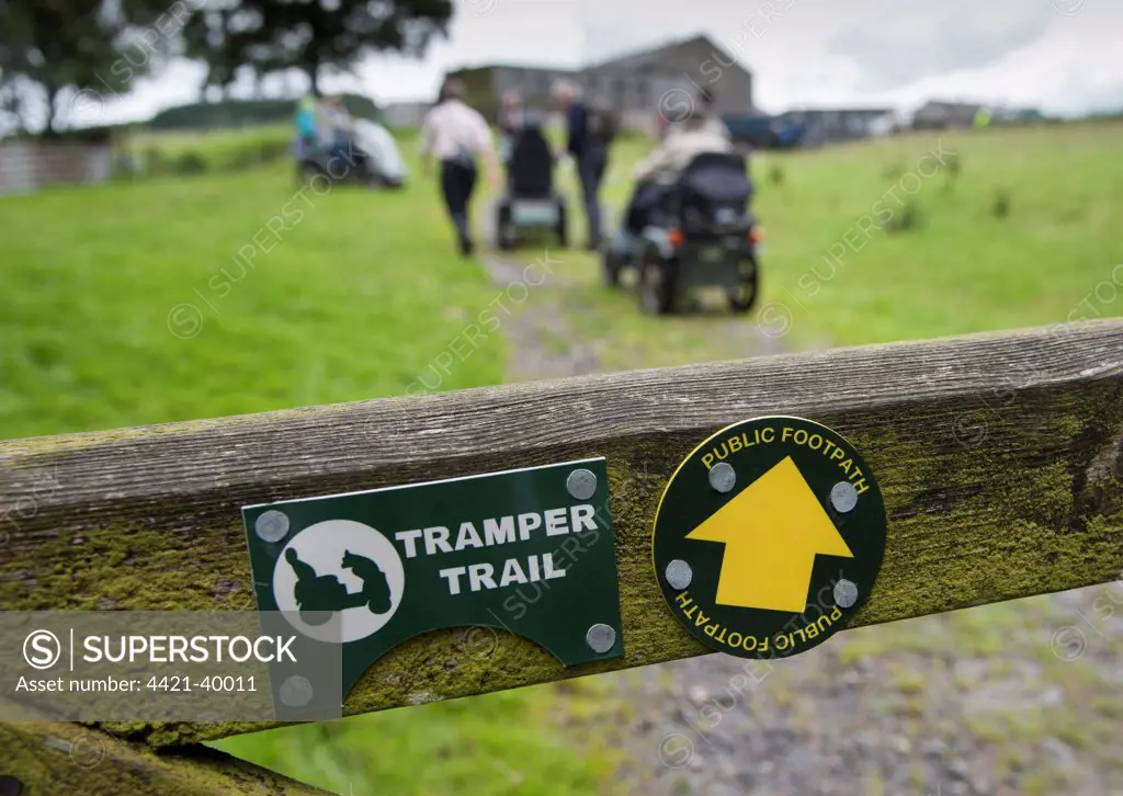 'Tramper Trail' and 'Public Footpath' signs on gate, people with mobility problems using 'Trampers' (all terrain mobility scooters) to visit farm, Whitewell, Forest of Bowland, Lancashire, England, july