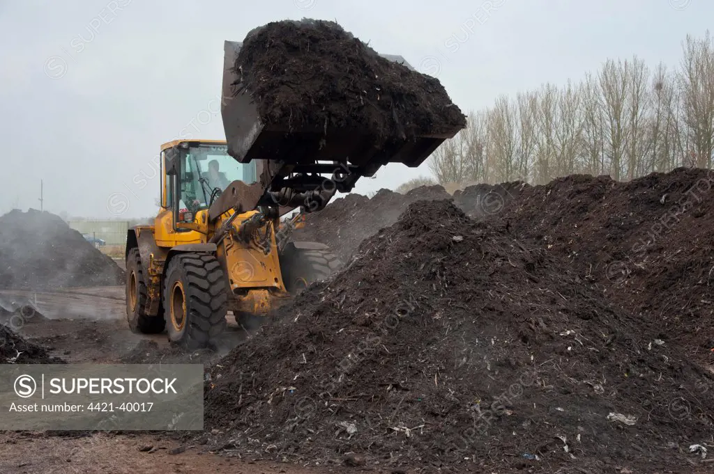 Volvo loader turning green compost waste for aeration at municipal waste site, near Chester, Cheshire, England, march