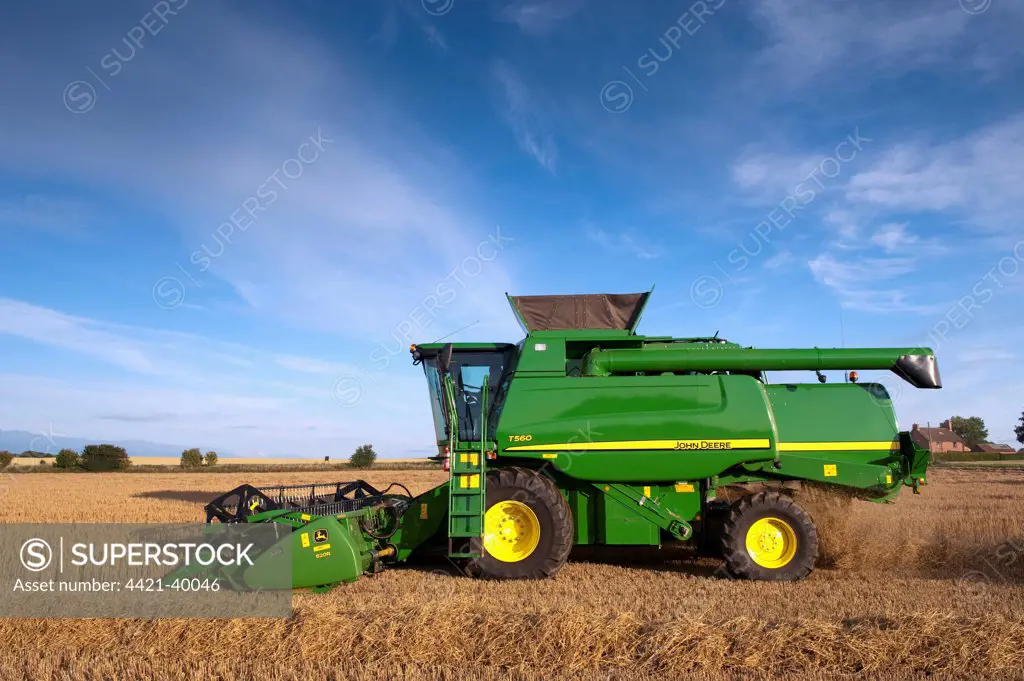 John Deere combine harvester, harvesting Barley (Hordeum vulgare) crop, discharging chaff and straw waste from back, England, july