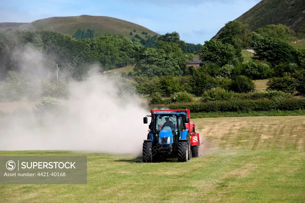 Tractor with muckspreader, spreading chicken manure mixed with lime on newly harvested meadow, England, june