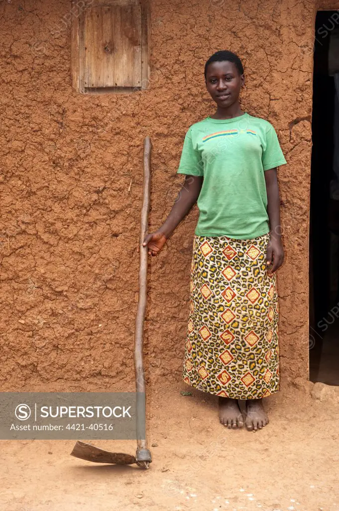 Lady with hoe, standing outside home, Rwanda