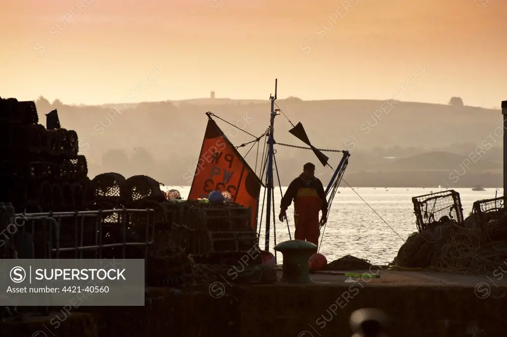 Fisherman preparing to go to sea at dusk, in harbour of seaside town, Padstow, Cornwall, England, april