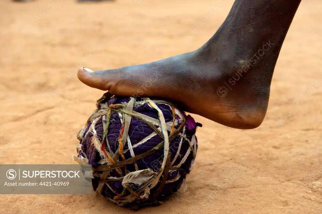 Child playing football with homemade ball, close-up of foot, Rwanda