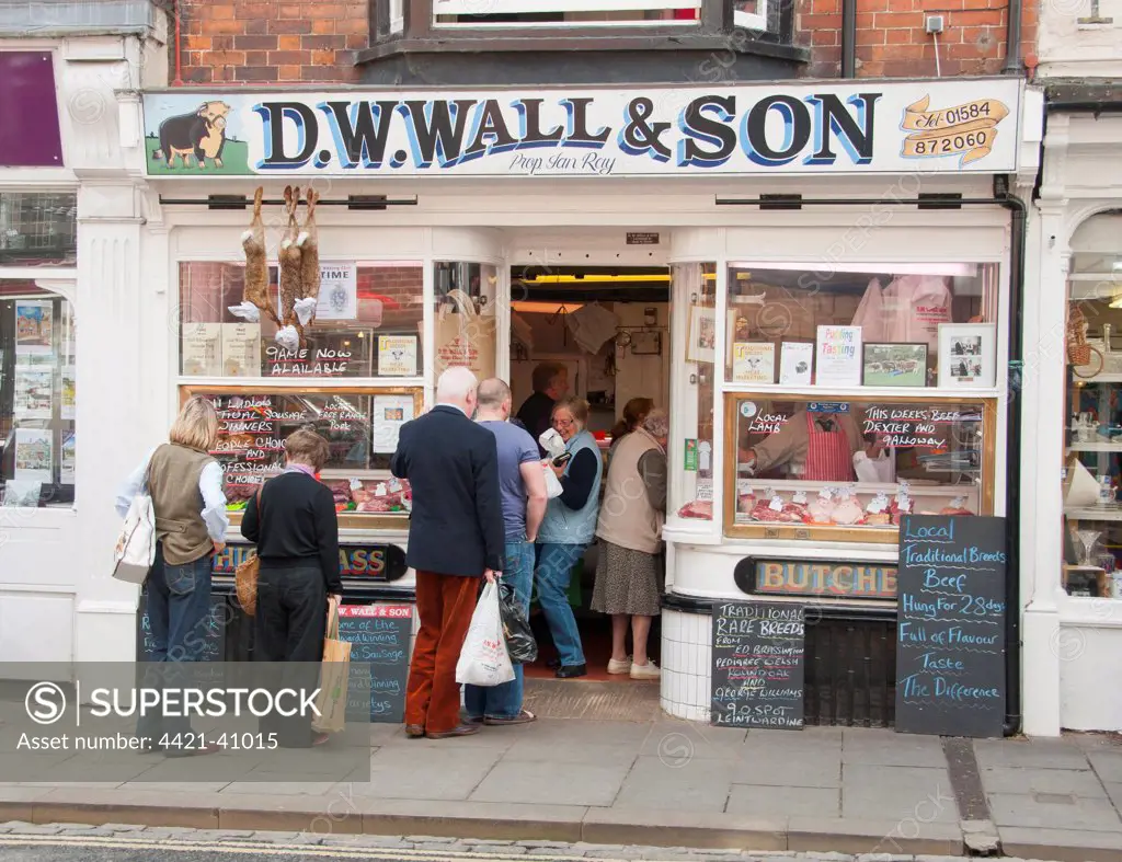 Customers queueing outside traditional butcher's shop, Ludlow, Shropshire, England, september
