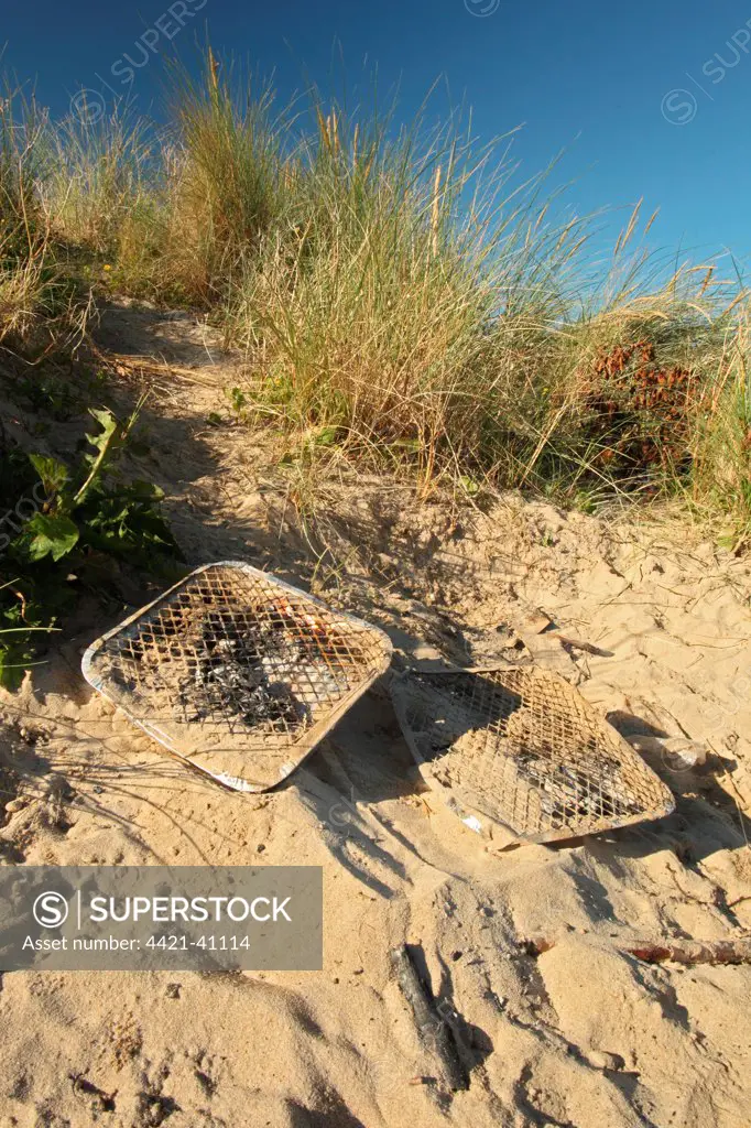 Disposable barbeques, litter on coastal sand dunes, Rock, Cornwall, England, july