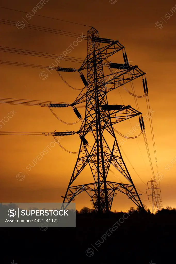 Electricity pylon and overhead wires, lit at night by light pollution from city of Leicester, Leicestershire, England