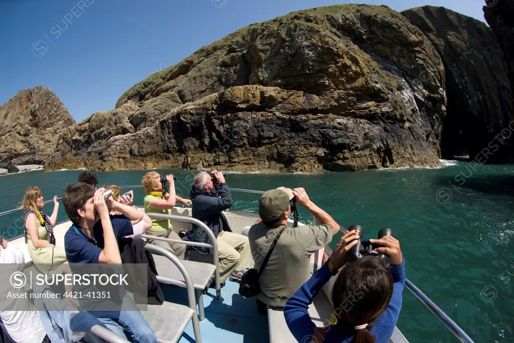 Birdwatchers with binoculars in boat, Ramsey Island, St. David's Peninsula, Pembrokeshire, Wales, june