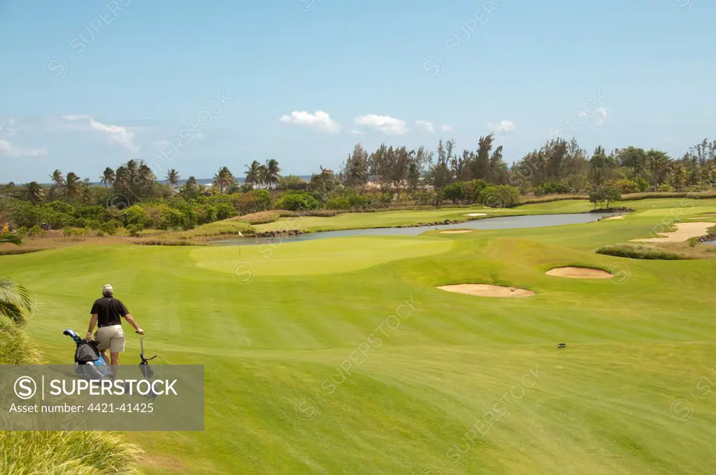 Golfer pulling golf cart across golf course, Le Telfair Hotel and Golf Course, Bel Ombre, Southwest Mauritius