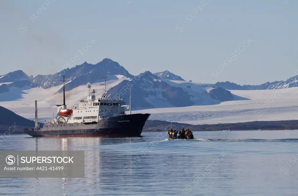Zodiac inflatable boat with tourists approaching cruise ship, with glacier in background, Spitzbergen, Svalbard, july