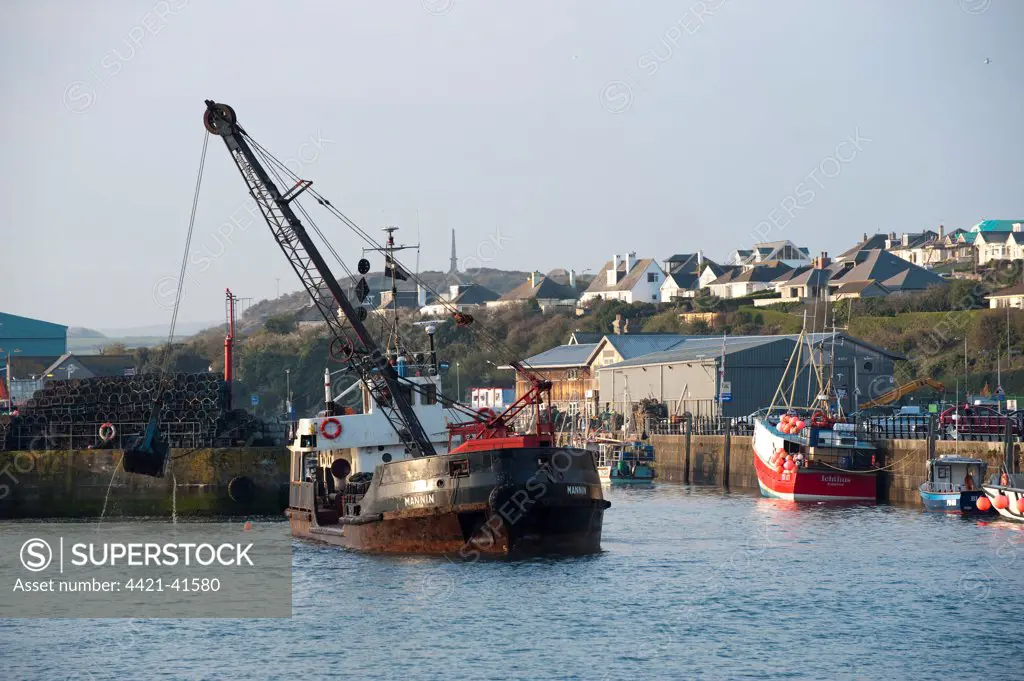 Dredger at work, dredging harbour of seaside town, Padstow, Cornwall, England, april