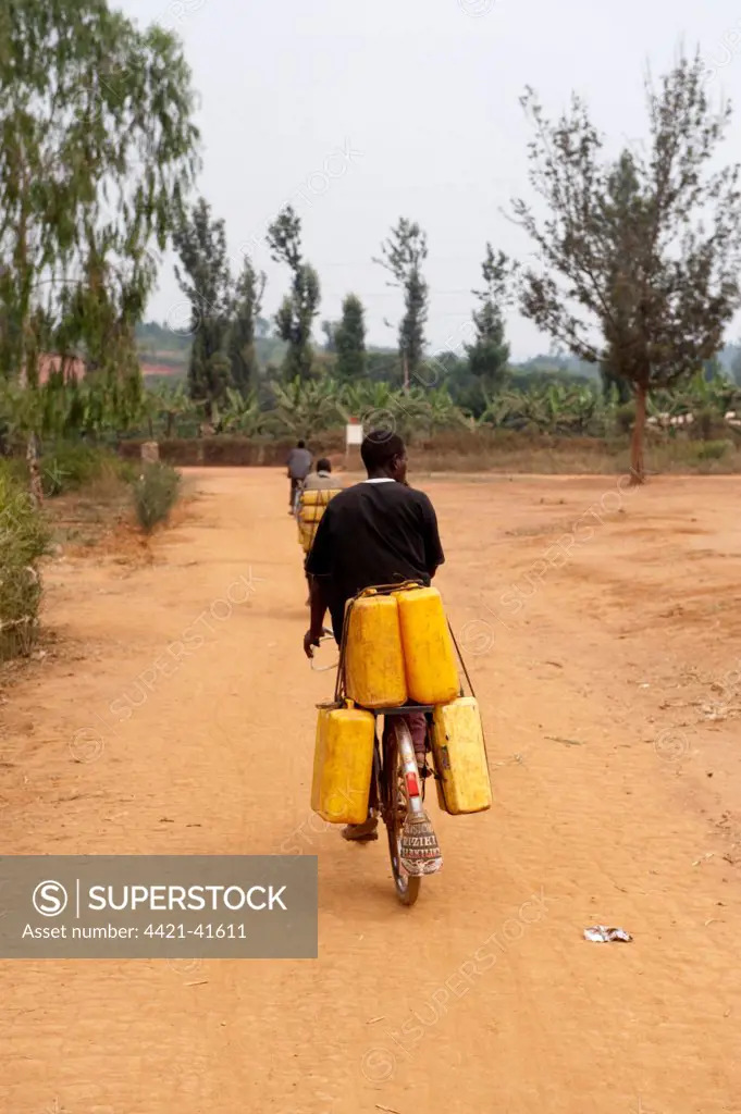 Cyclist carrying heavy water containers along track, Rwanda