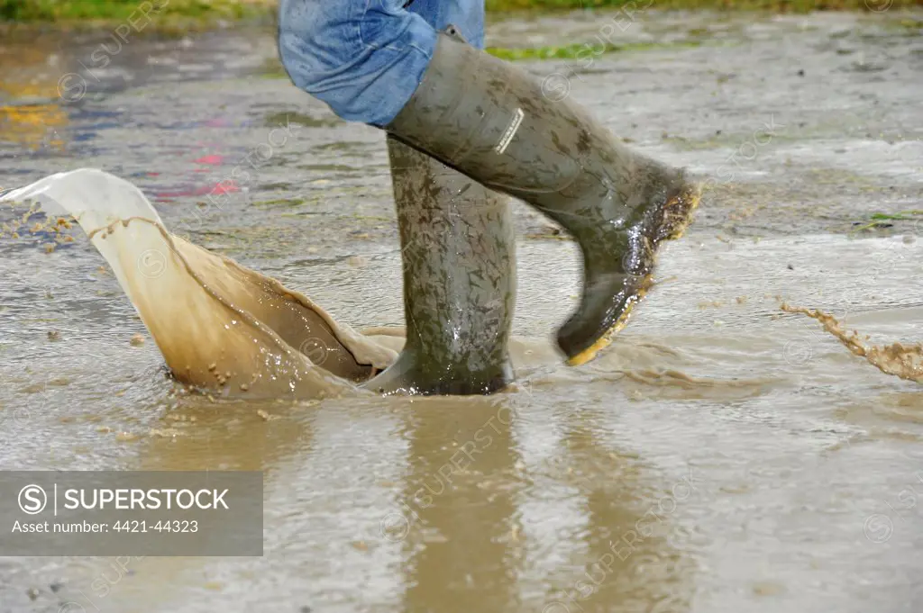 Person walking with wellington boots through puddle at agricultural show, Yorkshire, England, July