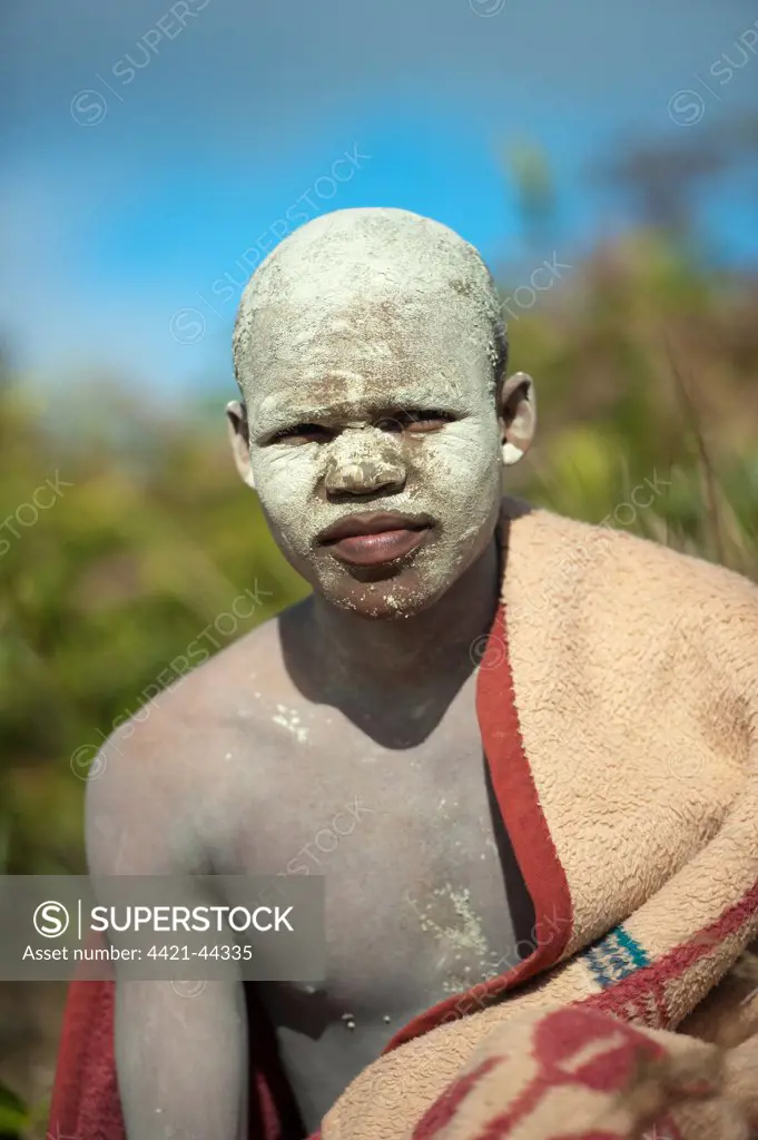 AmaPondo (Xhosa) boy wrapped in rugs with white clay (I-Futa) on face, after being circumcised (uku-Lukwa) and having finished initiation / seclusion period during which they are known as aba-Kweta and have been presented to their families as men (in-Doda), Umzimvubu Valley, Mkanzeni District, Pondoland, Eastern Cape (Transkei), South Africa, July