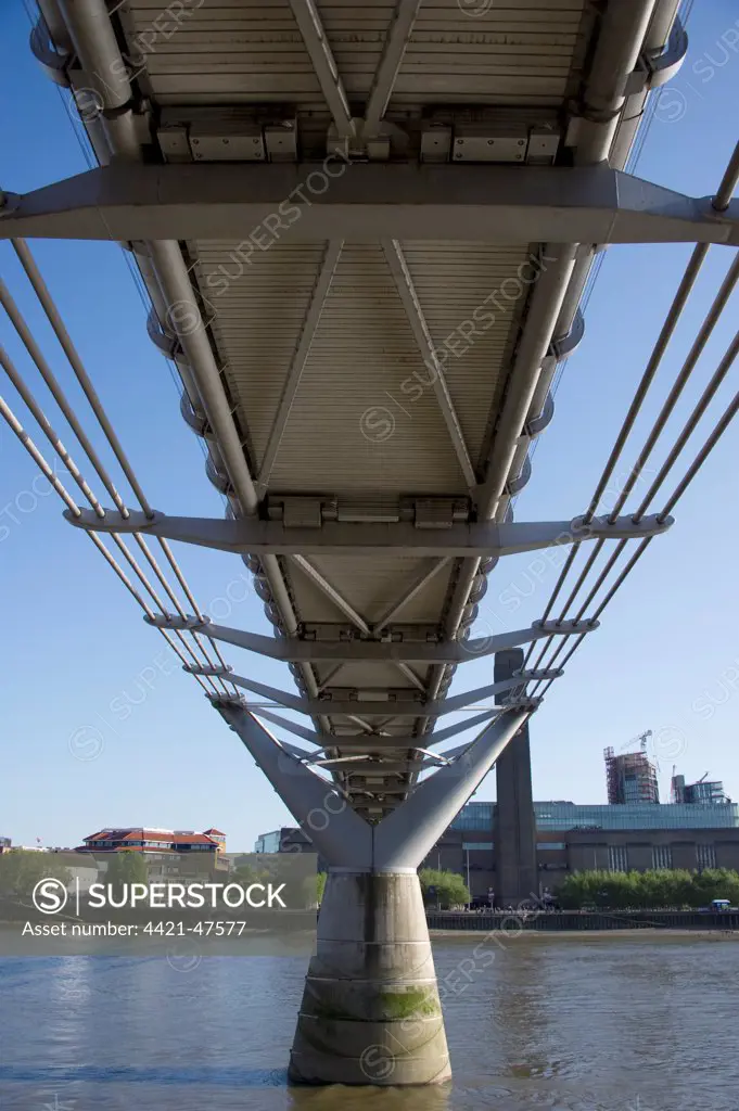 Underneath steel suspension footbridge crossing river, Millennium Bridge, River Thames, London, England, april