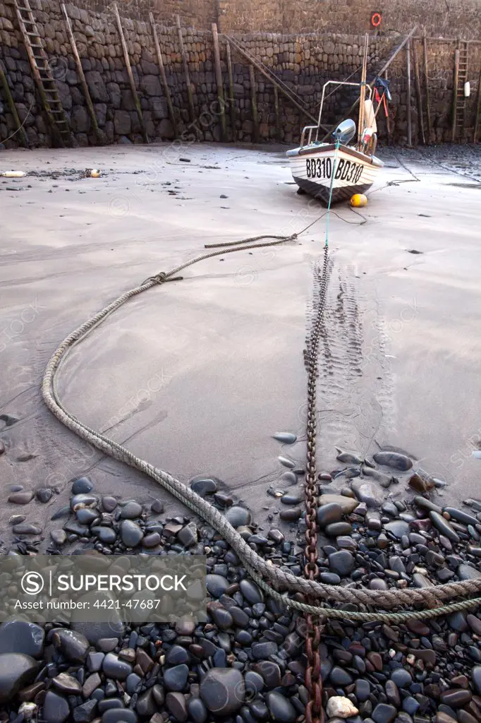 Small fishing boat on sand, moored in village harbour at low tide, Clovelly, Torridge, North Devon, England, May