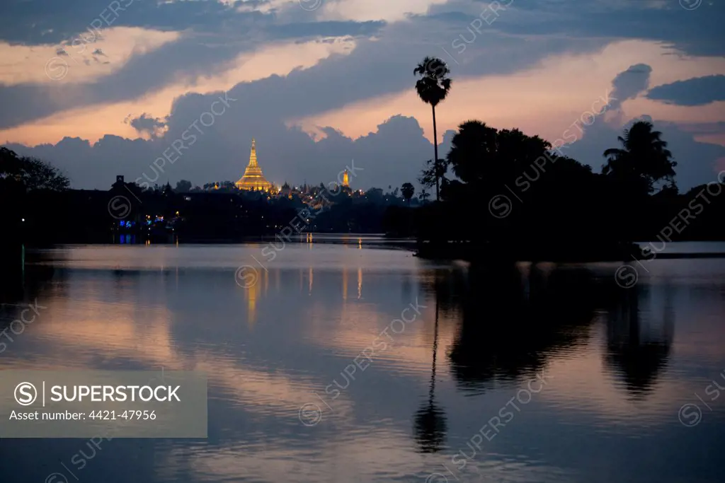 View of Shwedagon Pagoda across lake at sunset, Kandawgyi Lake, Yangon, Myanmar, March