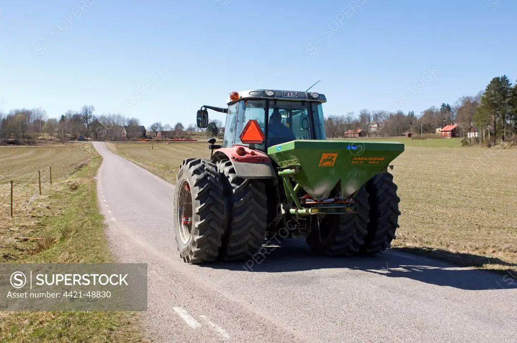 Tractor with Amazone ZA-F fertiliser spreader, driving along rural road, Sweden, spring