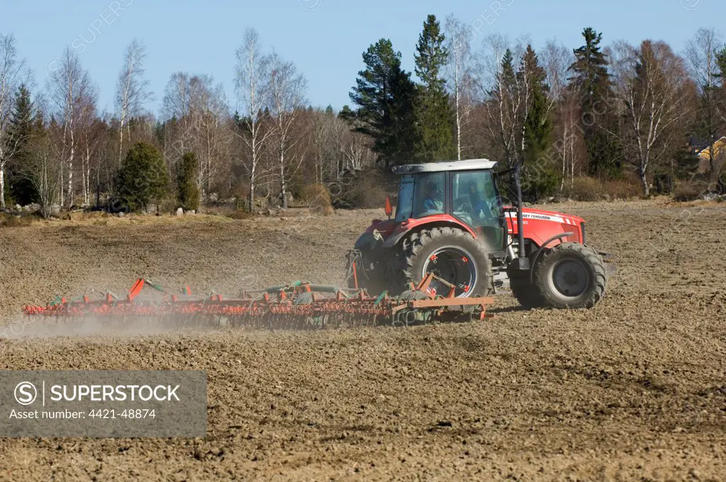 Massey Ferguson tractor pulling harrows, harrowing field, Sweden, spring