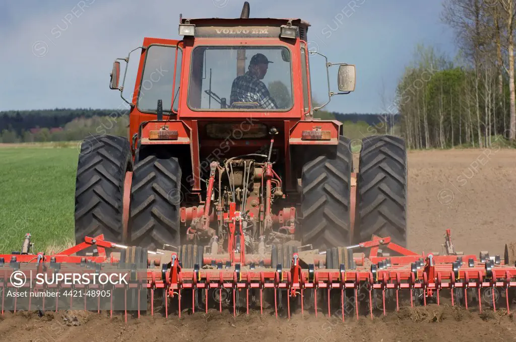 Volvo tractor pulling harrows, cultivating arable field, Sweden
