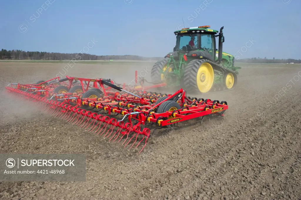 John Deere 8320 RT tracked tractor with Vaderstad NZA-1000 harrows, harrowing arable field, Sweden, april