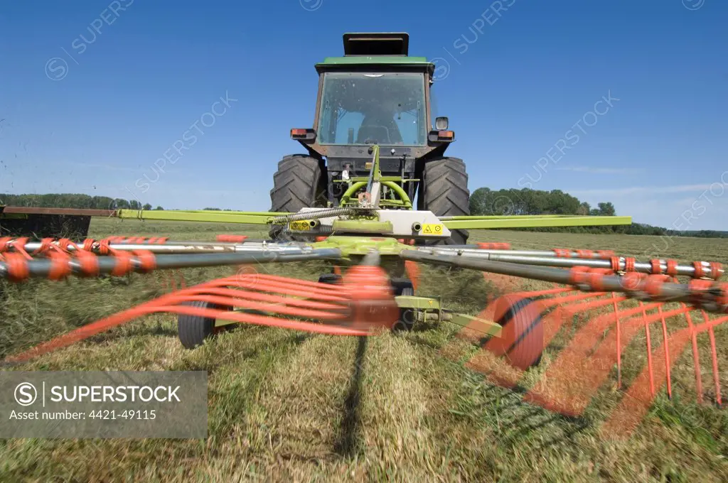 Tractor with Claas Liner 350 rotary rake, turning cut grass for silage crop, Sweden